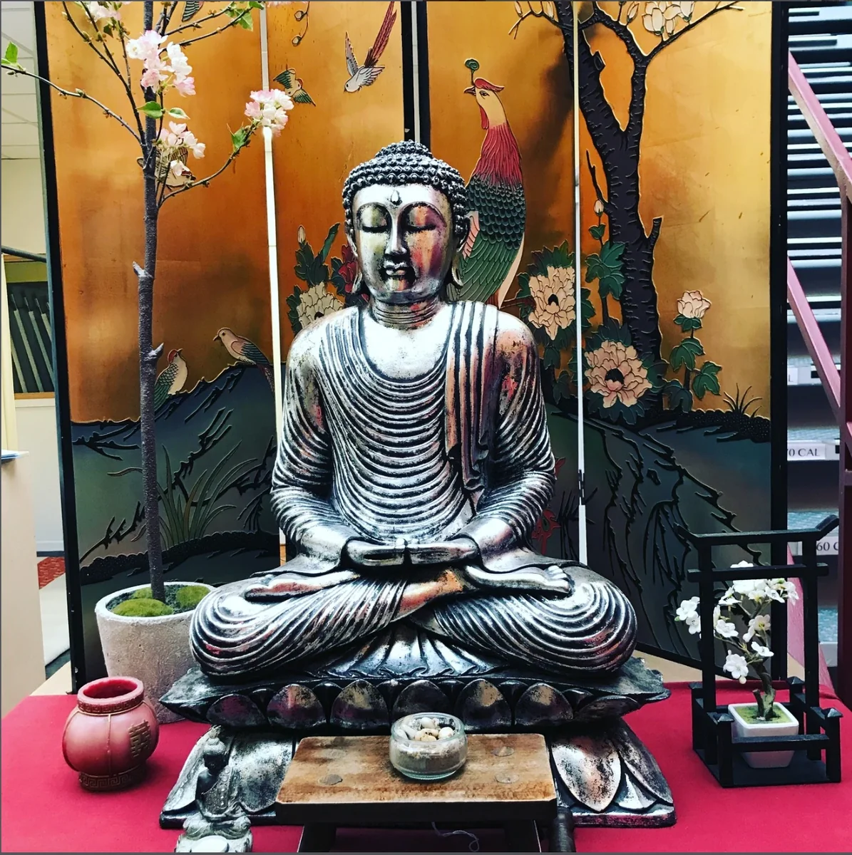 Statue de Bouddha en méditation devant un paravent doré, dans les locaux de Shiatsu Nord